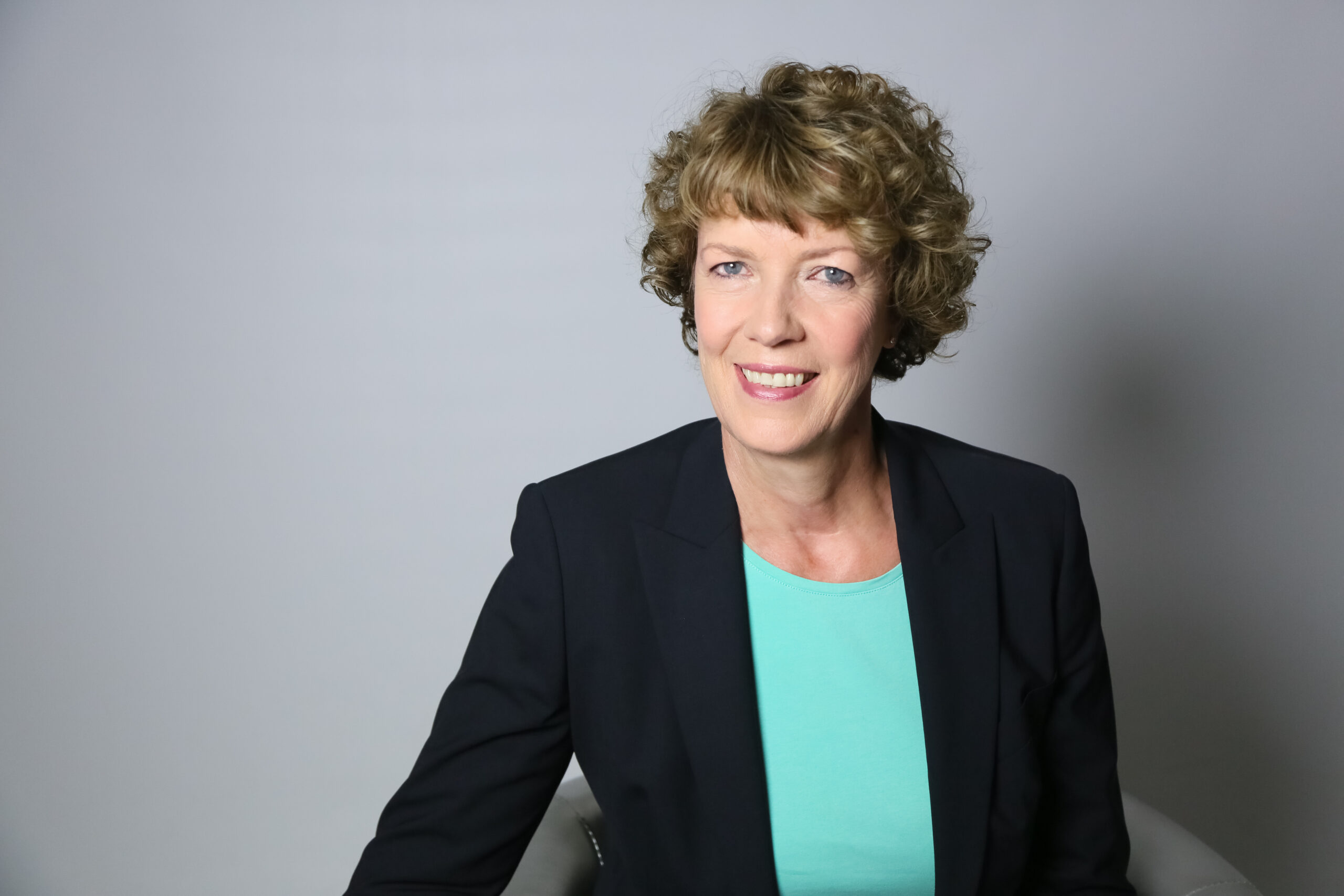 Ulrike Schweer sitzt mit einem Blazer und schaut nach Links